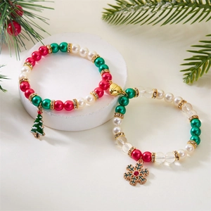 Detailed view of Christmas beaded bracelet with festive tree and snowflake charms on a white stand