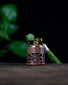 Detailed macro view of a carved sandalwood pendant with green tassels and jade beads