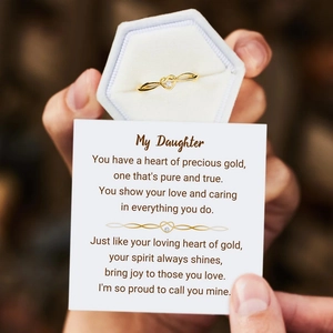 Close-up of golden heart and infinity ring with a gift card for daughter in a velvet box
