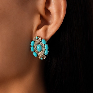 Close-up of vintage gold earrings with turquoise stone and zircon on a female model