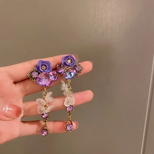 Detailed close-up of purple flower drop earrings with artificial crystal accents