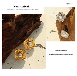 Detail of 18K gold plated clover earrings with hammer texture and white pearl center