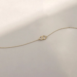 Macro detail of intertwined double rings on a delicate gold chain necklace