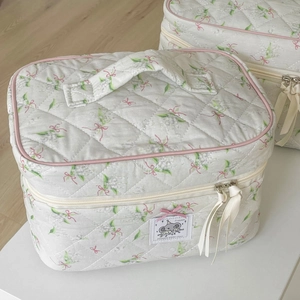 Close-up of quilted cosmetic bag featuring ribbon zipper pulls and cute floral pattern