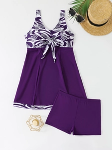Deep purple tankini set with abstract print and shorts on a summer beach background