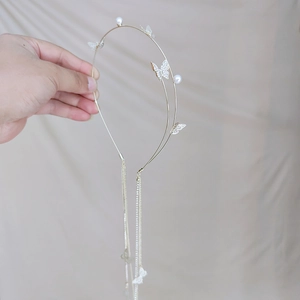 Detail of golden headband with pearl beads, butterfly charms, and long tassel chains