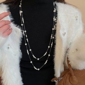 Close-up of double-layer pearl necklace with rhinestone beads on a black knit sweater