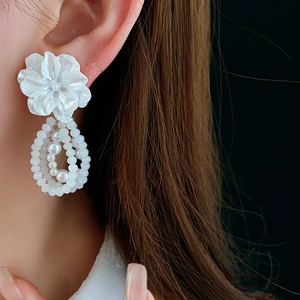 Close-up of elegant flower earrings with multilayered white pearl bead drop pendants