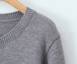 Gros plan d'un gilet gris en maille à col rond montrant la texture fine du tissu