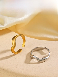 Macro shot of minimalist gold and silver wavy open rings on a stone textured surface