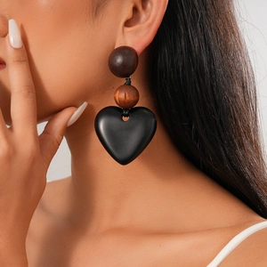 Macro shot of stylish wooden earrings featuring brown beads and a black heart pendant
