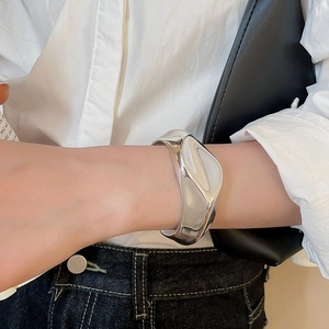 Close-up of a silver irregular wrinkled open cuff bracelet on a female wrist