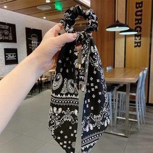 Detail of black and white paisley hair scrunchie with long ribbon scarf attachment