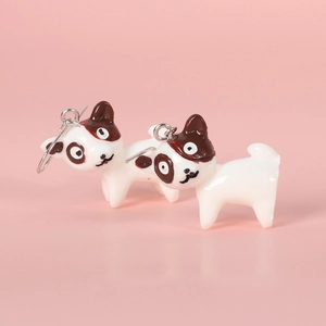 Close-up of cute cartoon dog earrings with glossy resin finish and metal hooks