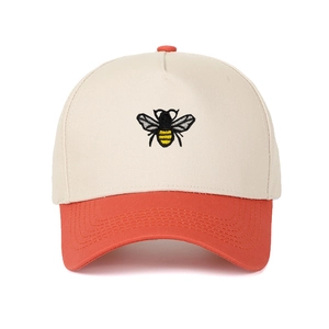 Detailed close-up of a bee embroidery on a color-block cotton five-panel trucker hat