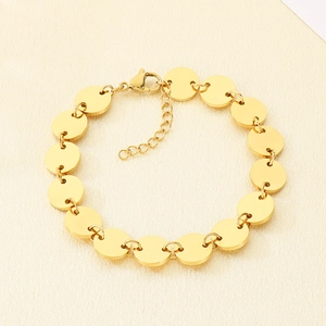 Detailed view of golden round disc link bracelet with adjustable lobster clasp on fabric