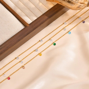 Detailed view of three gold titanium steel necklaces with colorful round charms on silk