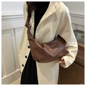 Detail of large brown leather crescent crossbody bag featuring soft lychee grain texture
