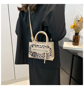 Close-up of stylish leopard print handbag with beige leather trim worn by a model