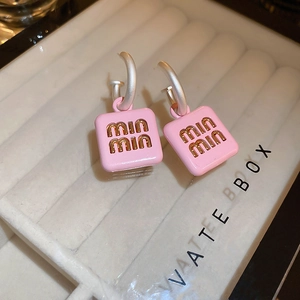 Detailed macro view of pink square earrings featuring golden embossed min min lettering