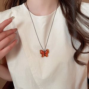 Dettaglio del ciondolo a farfalla ambra traslucida su una collana in stile retrò