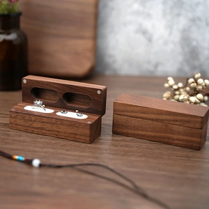 Detail of walnut wood jewelry box with double slots holding a diamond ring and earring