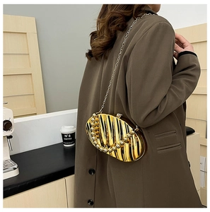 Close-up of golden shell-shaped acrylic evening bag with metallic texture on a model