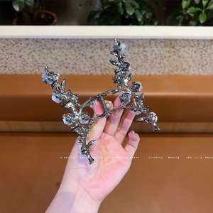 Détail d'une pince à cheveux florale en métal gris fusil avec de petites fleurs blanches