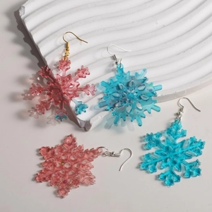 Detailed view of handmade snowflake resin earrings with sparkling glitter in pink and blue