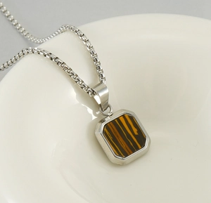 Vue détaillée du collier en acier titane argenté avec pendentif carré en oeil de tigre