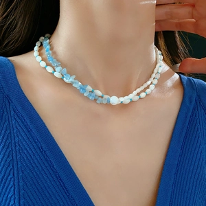 Detail of double-layer necklace with white beads and light blue aquamarine stones