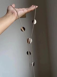 Detailed view of silver-tone tassel necklace with five polished geometric circular discs