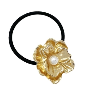 Elastic black hair tie with gold metal flower and pearl accent on white background
