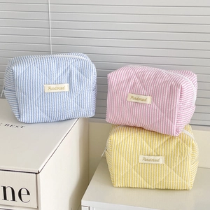 Three candy-striped quilted cosmetic bags in pastel blue, pink, and yellow cotton