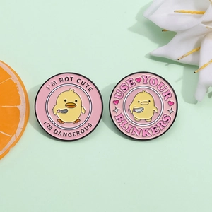 Pink round enamel pin with cartoon yellow duck and 'I'm not cute' letter slogan