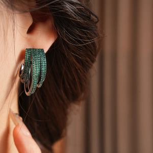 Close-up of sparkling green zircon multi-layer C-shaped hoop earrings on model
