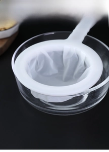 Detail of ultra-fine kitchen mesh strainer placed over a glass bowl for soy milk filtering