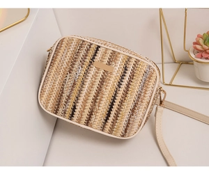 Macro detail showing woven straw texture and gold metal buckle on a crossbody bag