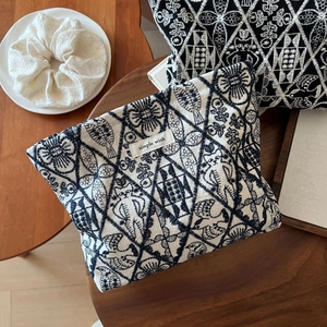 Detail of hand-embroidered linen makeup bag with cat patterns on wooden background