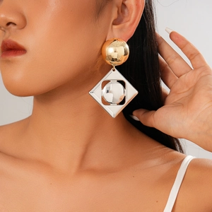 Close-up of geometric gold circle and silver diamond drop earrings worn by a model