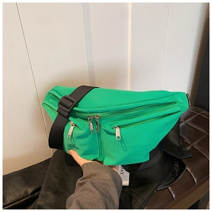 Detail of vibrant green nylon crossbody bag with adjustable wide strap and metal zippers