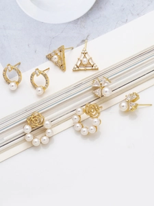 Close-up of pearl and zircon earrings in 18k gold plating on marble surface