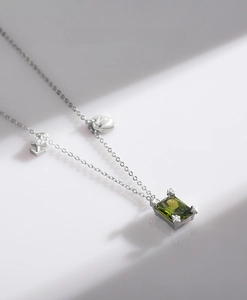 Detail of S925 silver necklace with emerald-cut green stone and star-shaped prongs
