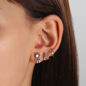 Close-up of cute astronaut, rocket and planet stud earrings set with colorful zircons