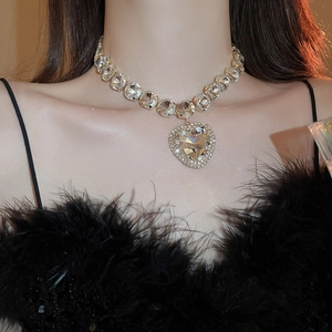 Close-up of gold heart pendant necklace with shimmering diamonds on elegant female model