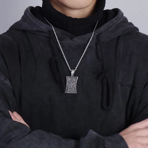 Nahaufnahme einer silbernen Om-Symbol-Halskette aus Titanstahl an einem männlichen Model