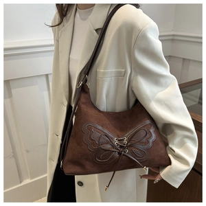 Detail of dark brown suede shoulder bag with butterfly applique and lace-up design