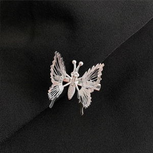 Detailed close-up of a silver metal butterfly hair clip with intricate hollow patterns