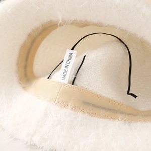 Detalle macro del suave material de felpa blanca y la etiqueta de tela de este gorro bucket