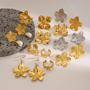 Flat lay of floral design earrings and rings in gold and silver with pearl accents